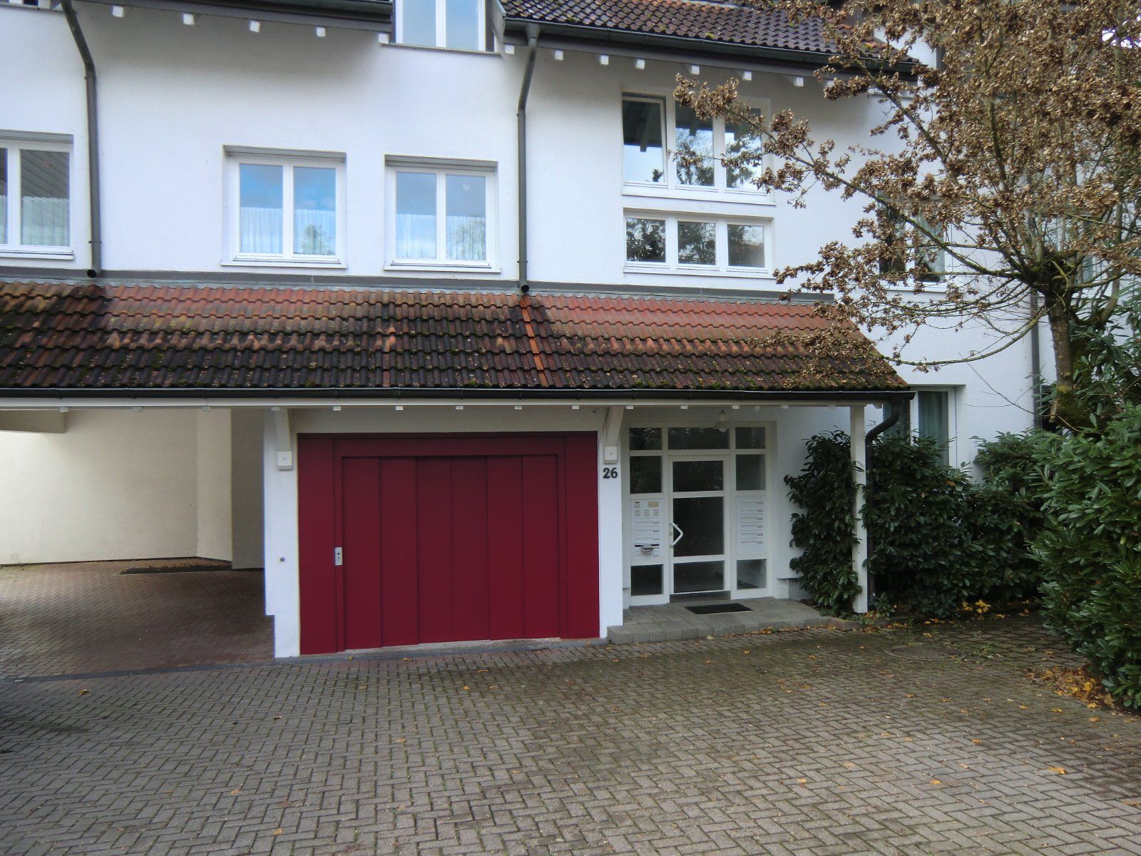 Außenansicht eines Hauses mit rotem Garagentor und Eingang