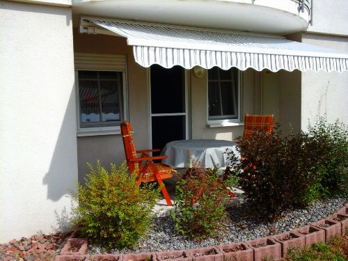 Terrasse mit Tisch und Stühlen im Grünen, teilweise überdacht
