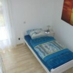 Einzelzimmer in der Ferienwohnung Ahorn mit Einzelbett und einem Wandbild eines Sonnenuntergangs. Helle Farben und viel Tageslicht sorgen für eine angenehme Atmosphäre.