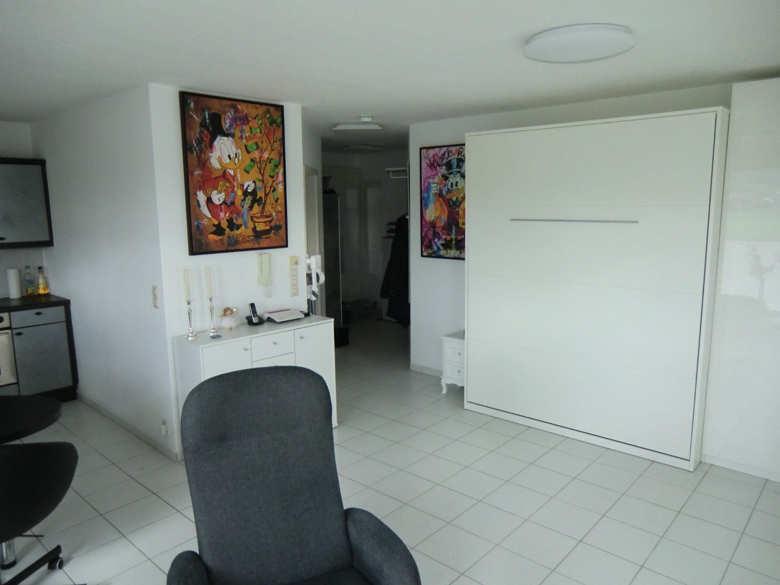 Zimmer mit Klappbett und modernen Kunstdrucken an der Wand