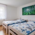 Helles Schlafzimmer mit zwei Einzelbetten und einem Wandbild eines Waldes