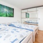 Helles Schlafzimmer mit Doppelbett und großem Spiegel sowie Naturbild an der Wand