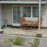 Die Terrasse der Ferienwohnung Ahorn mit einem Holztisch und Stühlen, ideal für entspannte Momente im Freien.
