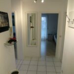 Flur in der Ferienwohnung Ahorn mit einem langen Spiegel, einer Garderobe und einem freundlichen Ambiente. Der Raum führt zu den Schlafzimmern der Wohnung.