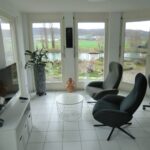 Wohnzimmer mit großen Fenstern und Blick ins Grüne