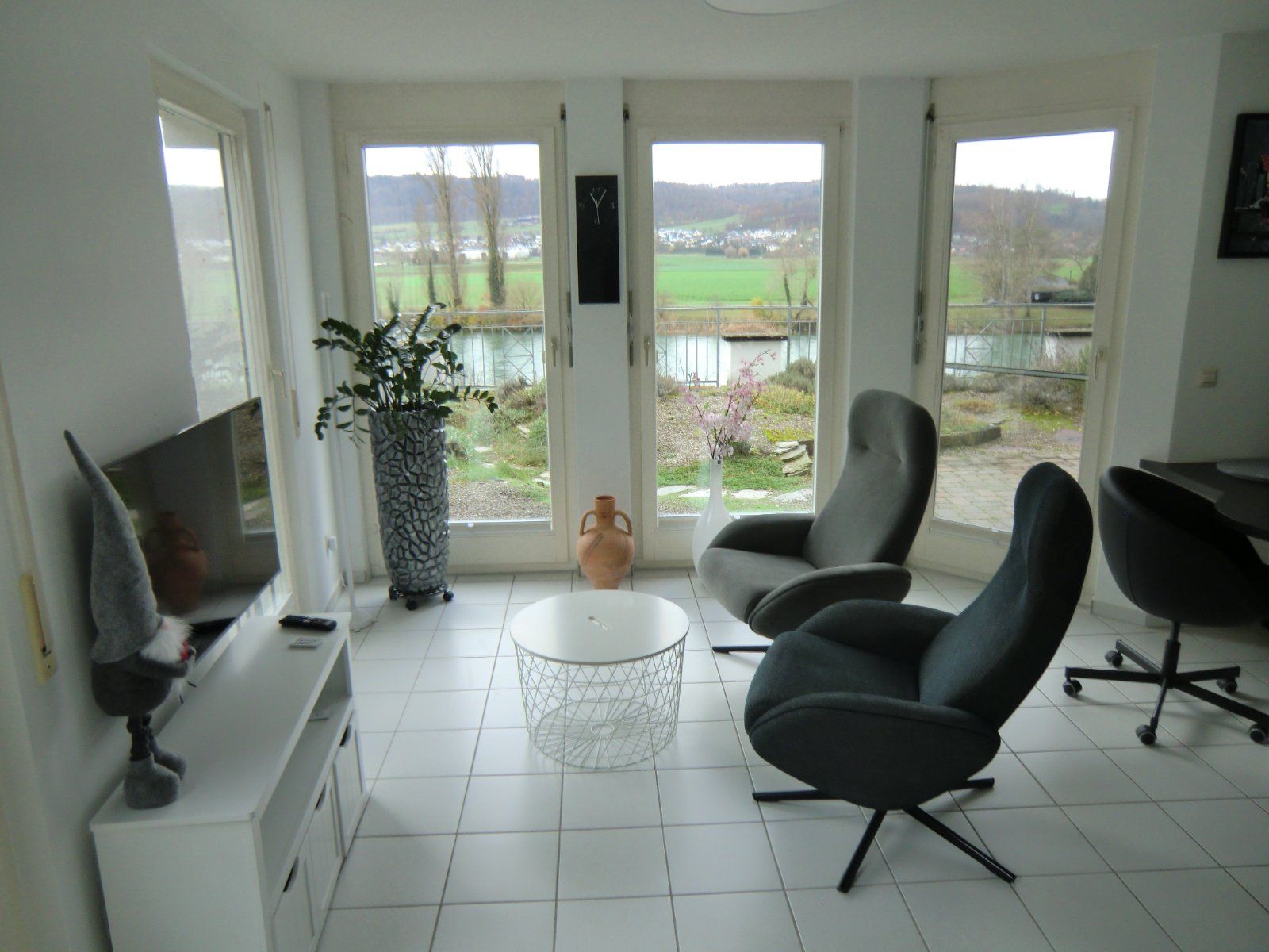Wohnzimmer mit großen Fenstern und Blick ins Grüne