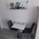 Gemütliche Essecke in der Ferienwohnung Brockmann in Küssaberg mit Tisch, zwei Stühlen und stilvoller Dekoration.