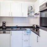 Moderne, kompakte Küche mit weißem Design und integrierten Geräten