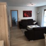 Wohnbereich der Ferienwohnung mit Sofa und Blick ins Schlafzimmer