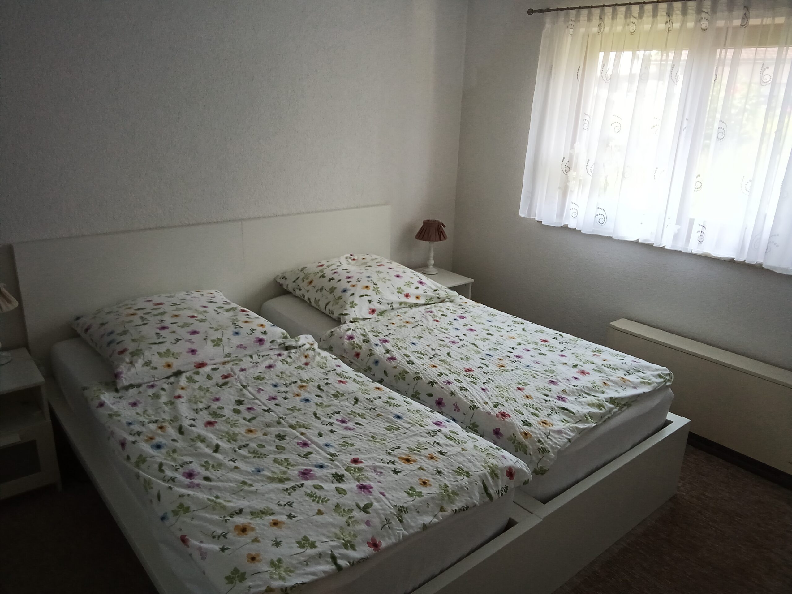 Helles Schlafzimmer mit zwei Einzelbetten und Blumenbettwäsche