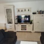 Wohnzimmer der Ferienwohnung mit modernem TV und rustikalen Schränken
