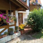 Terrasse der Ferienwohnung mit blühenden Pflanzen und rustikalem Charme.