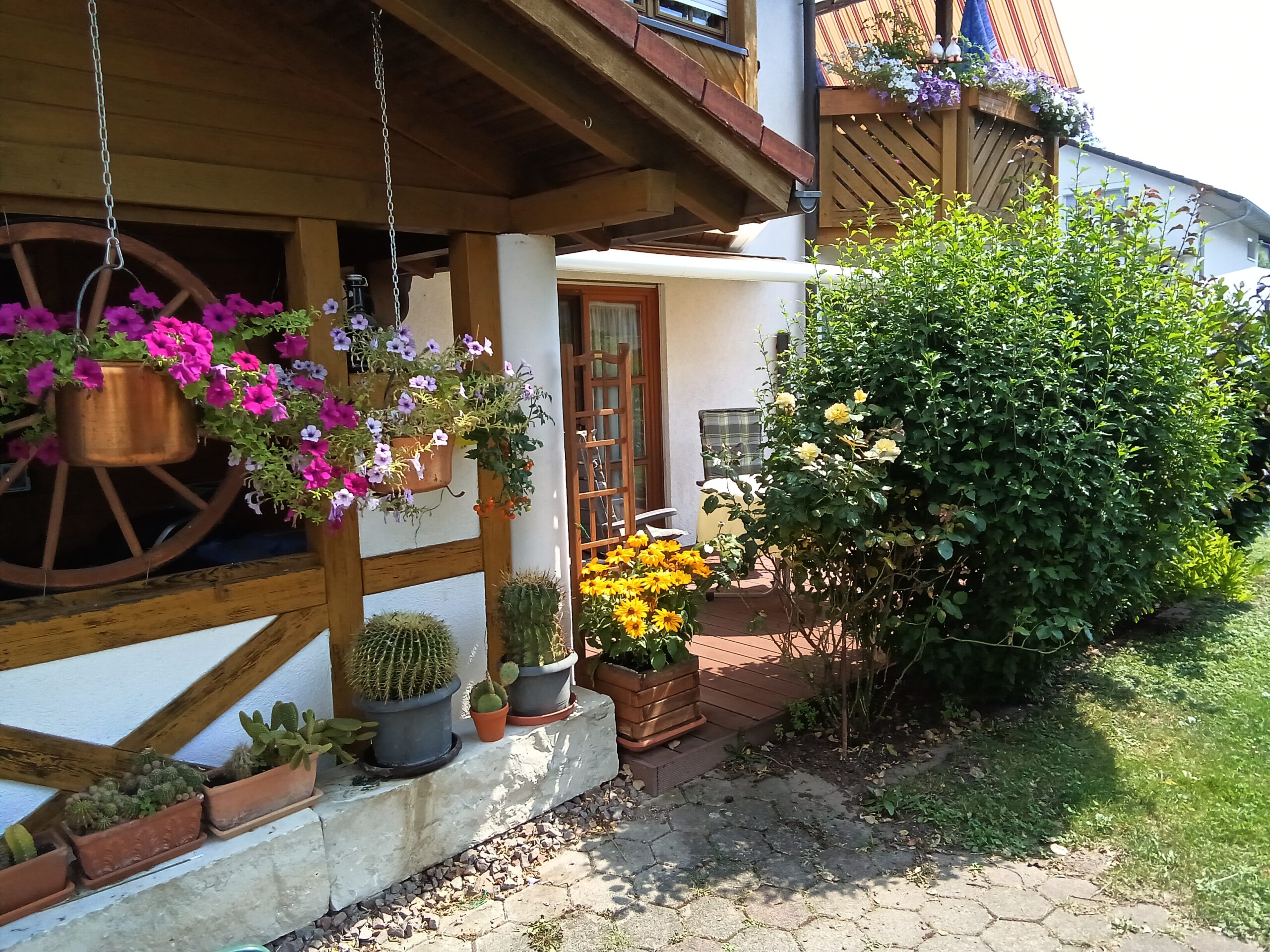 Terrasse der Ferienwohnung mit blühenden Pflanzen und rustikalem Charme.