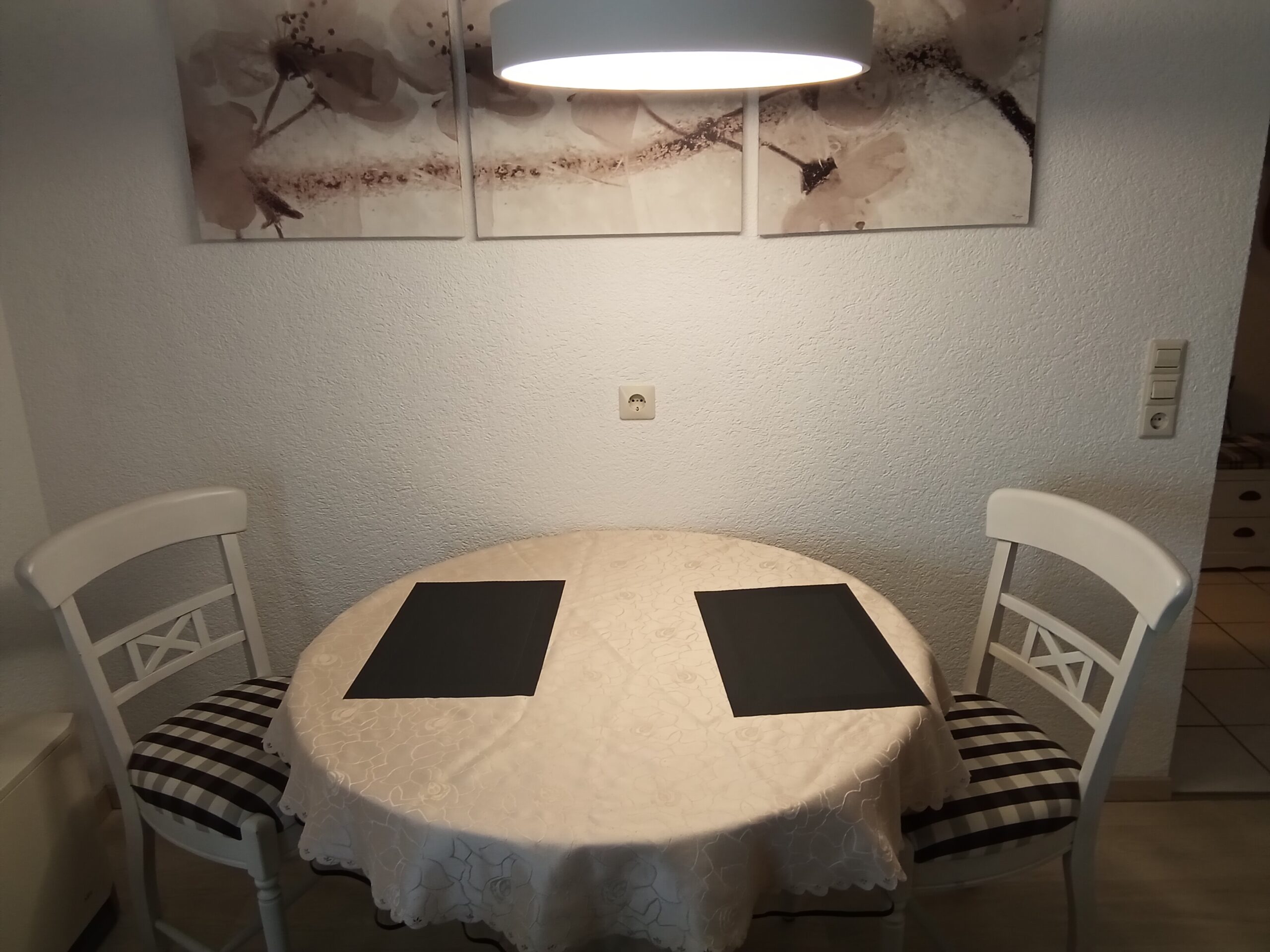 Kleiner Esstisch für zwei Personen mit dekorativen Platzsets und einer gemütlichen Beleuchtung.