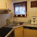 Kleine, gut ausgestattete Küchenzeile in der Ferienwohnung mit Herd, Spüle und Kaffeemaschine.