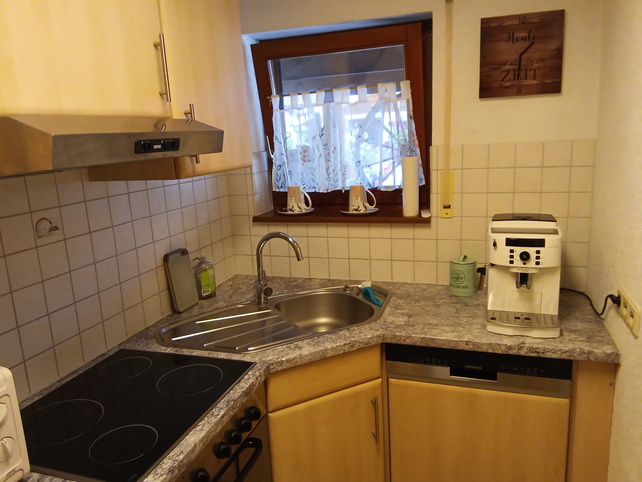 Kleine, gut ausgestattete Küchenzeile in der Ferienwohnung mit Herd, Spüle und Kaffeemaschine.