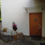 Eingang zur Ferienwohnung mit dekorativen Blumen und Herz-Ornament