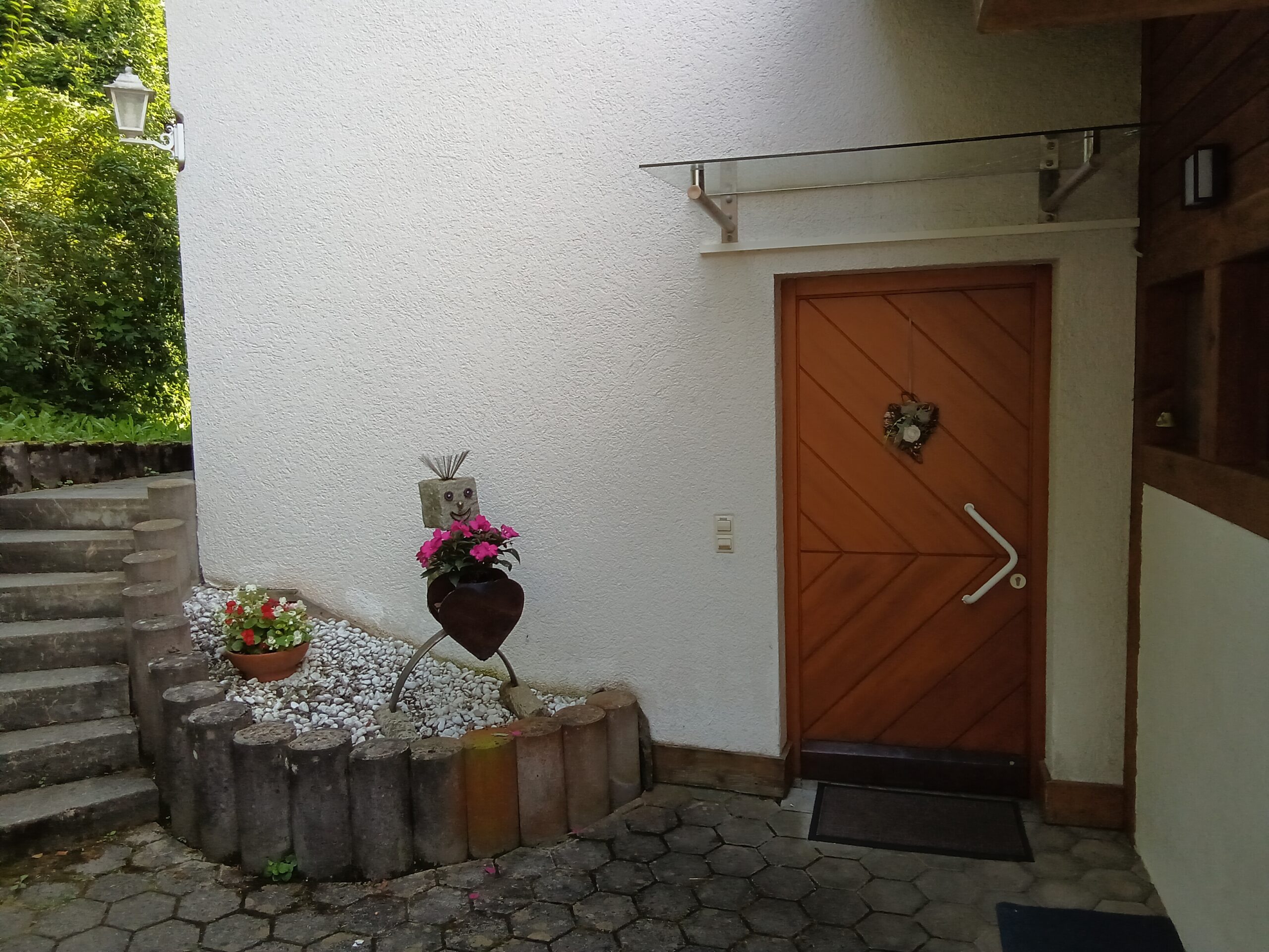 Eingang zur Ferienwohnung mit dekorativen Blumen und Herz-Ornament