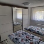 Schlafzimmer mit zwei Einzelbetten und großem Spiegelschrank in der Ferienwohnung Küssaberg