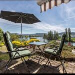 Terrasse mit Sitzbereich, Sonnenschirm und Blick auf den Rhein