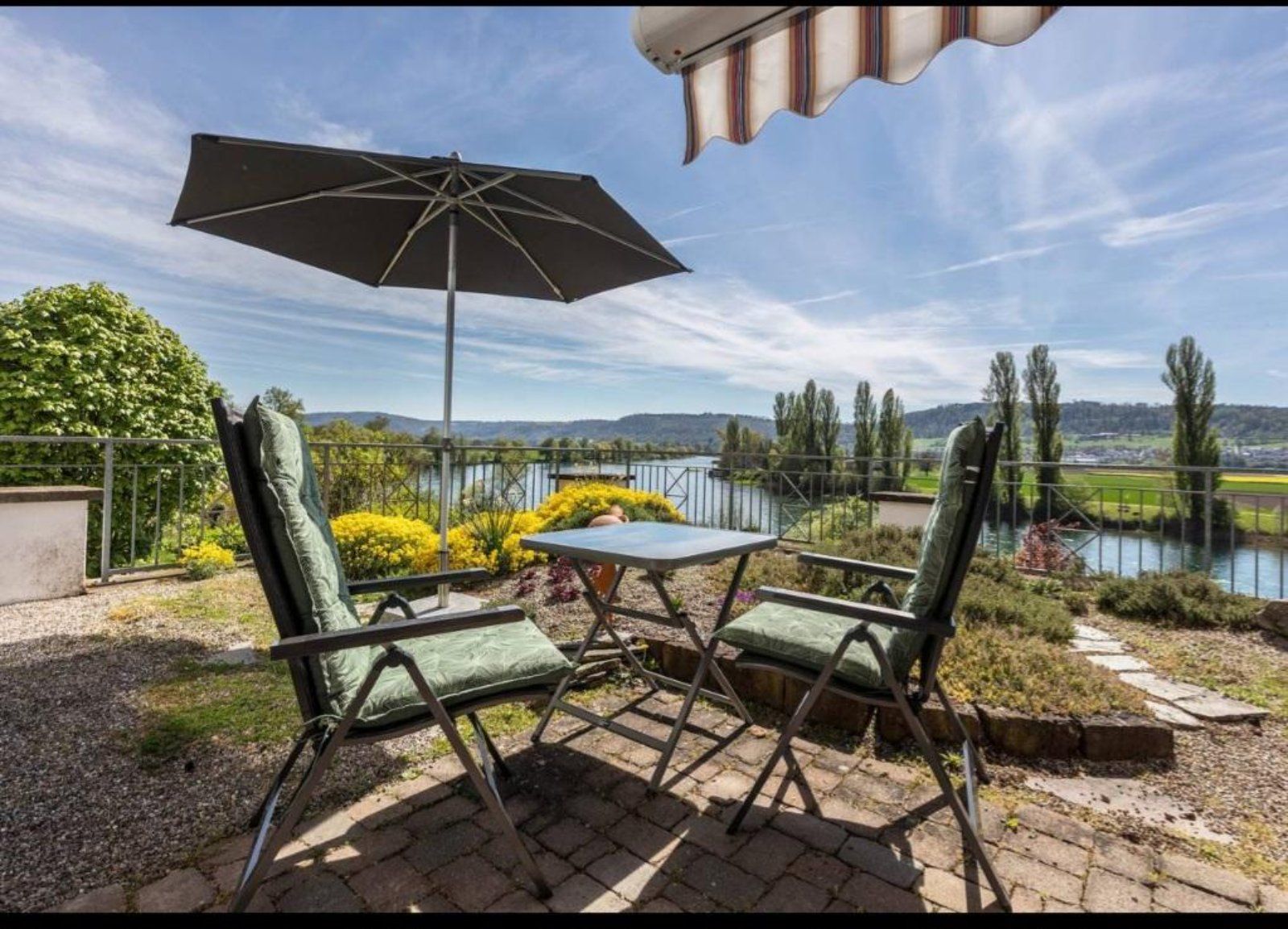 Terrasse mit Sitzbereich, Sonnenschirm und Blick auf den Rhein