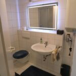 Modernes Badezimmer mit Waschbecken, beleuchtetem Spiegel und WC