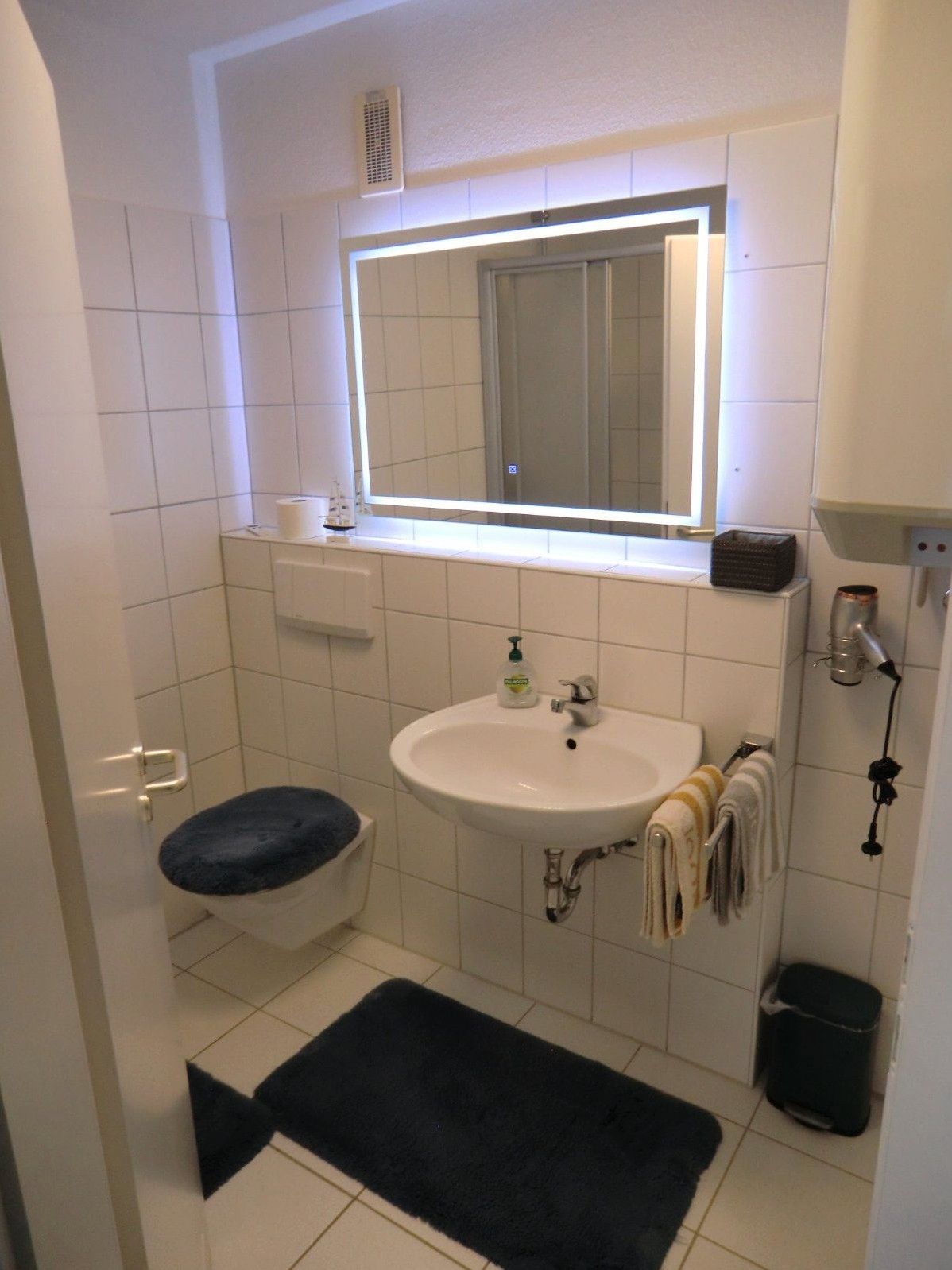 Modernes Badezimmer mit Waschbecken, beleuchtetem Spiegel und WC