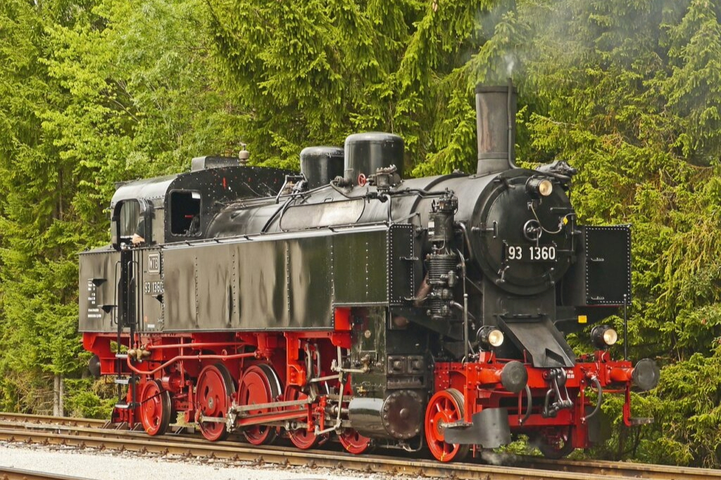 Historische Dampflok 93 1360 der Sauschwänzlebahn im Schwarzwald, schwarze Lok mit roten Rädern vor grünem Wald